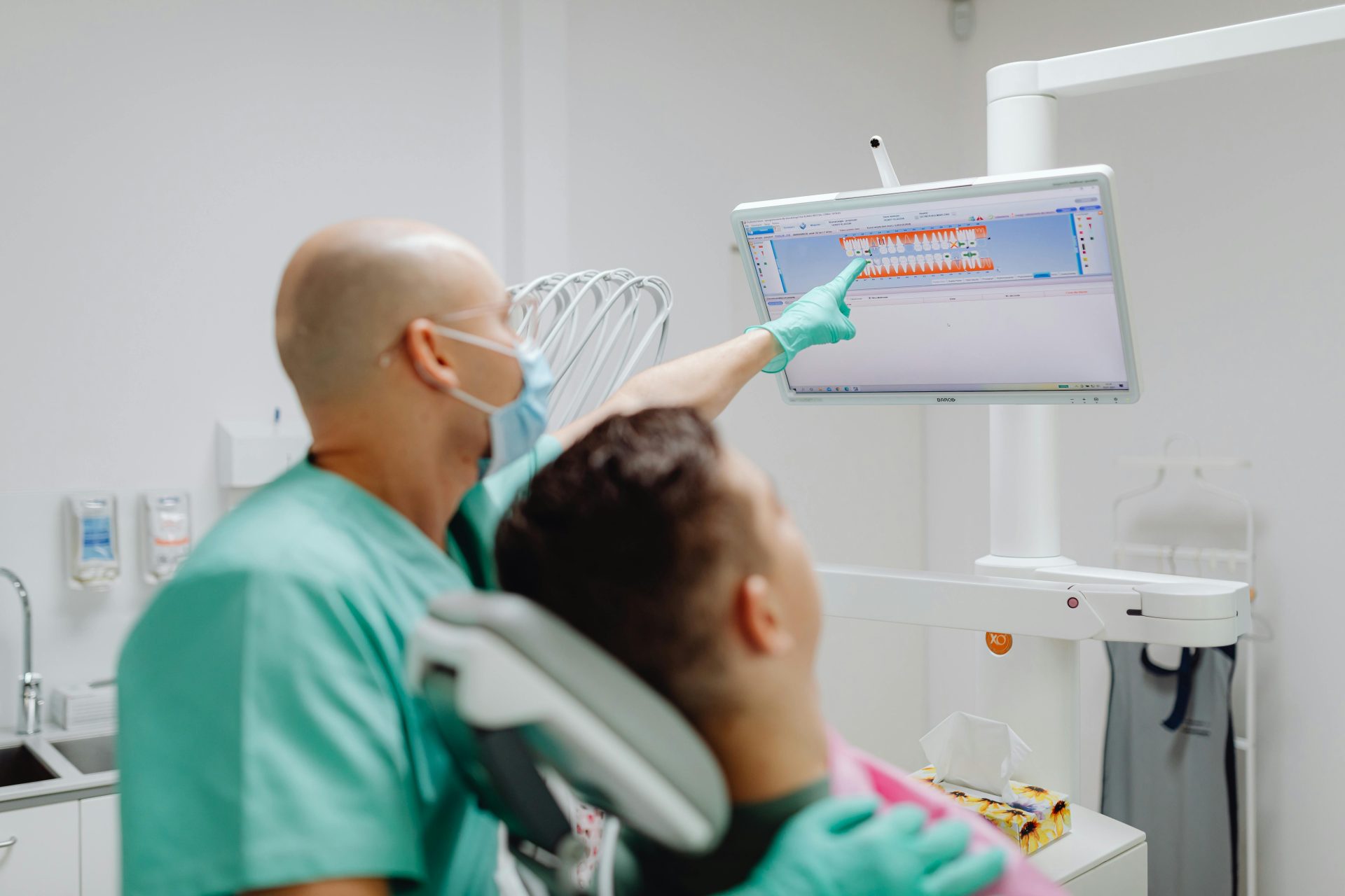 Dentista examinando a un paciente con software de imágenes dentales en una clínica moderna.